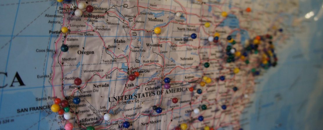 A map of the United States, with pins pushed into various areas as if indicating places visited.